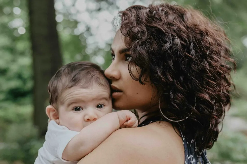 A mother holding her baby close outdoors