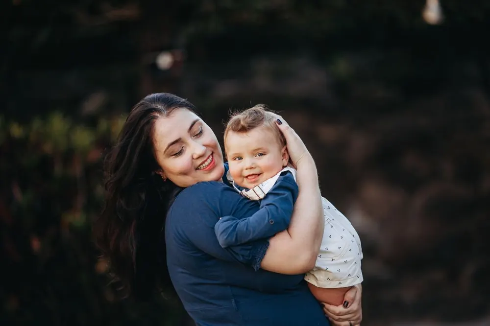 A mother and her smiling baby sharing a moment outside